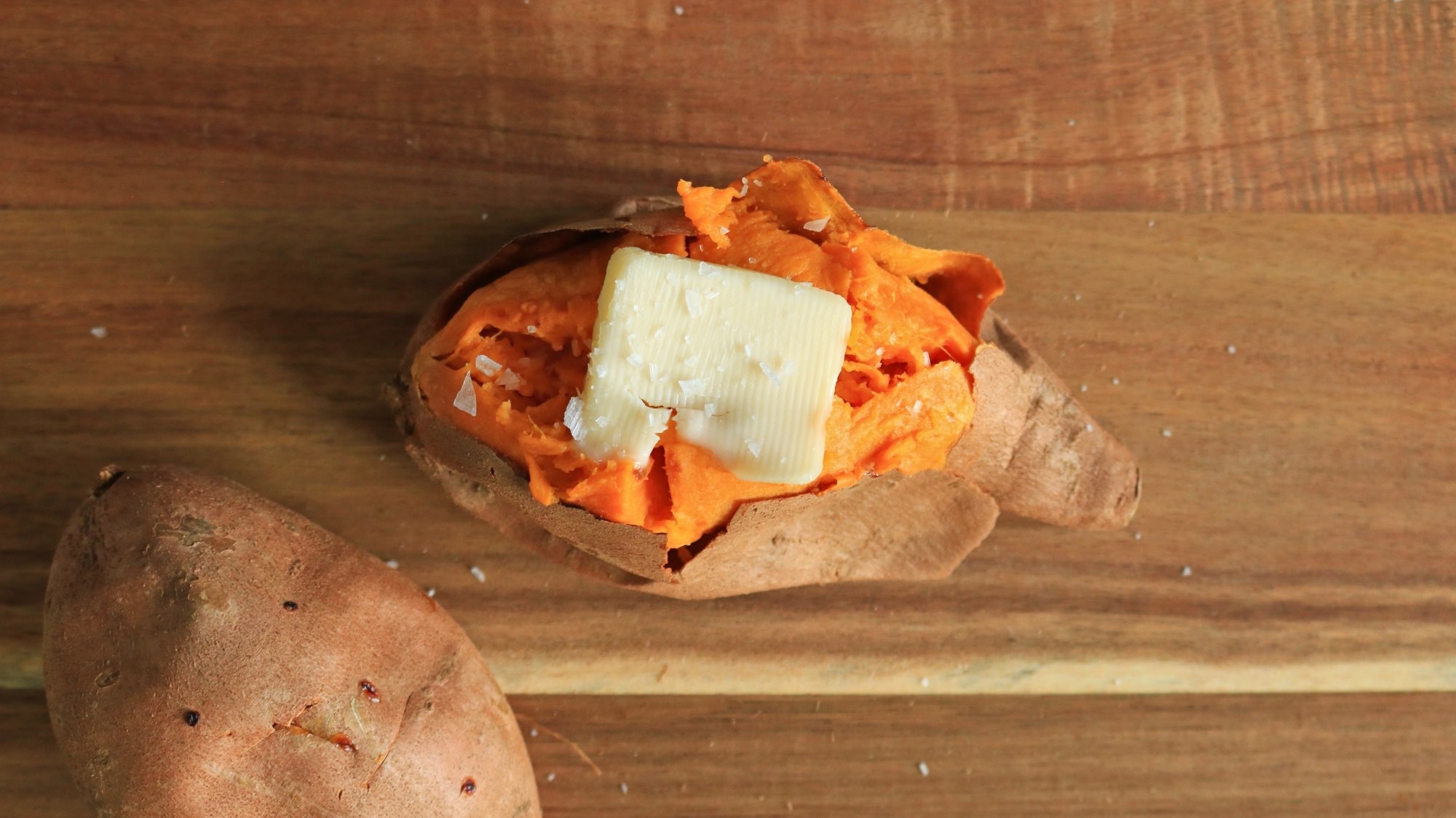 An open sweet potato with a slice of butter on top.