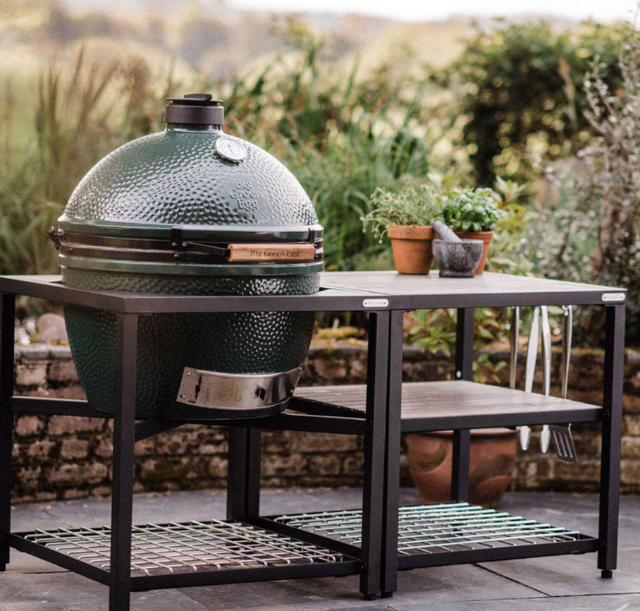 Green kamado grill in an outdoor patio setting.