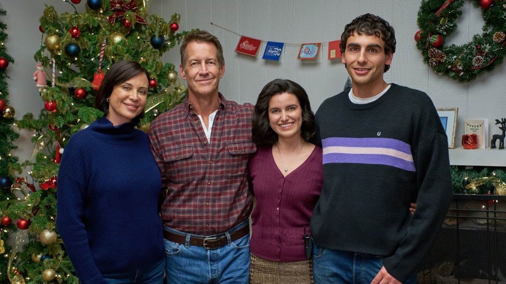 Four people stand side by side in front of a fireplace.