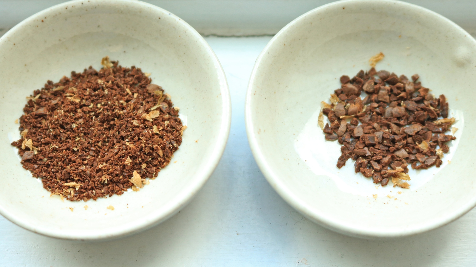 Two small bowls with ground coffee inside.